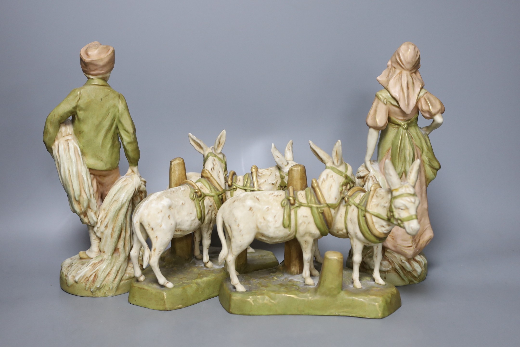 A pair of Royal Dux figures and a pair of Royal Dux donkey groups, 24cm